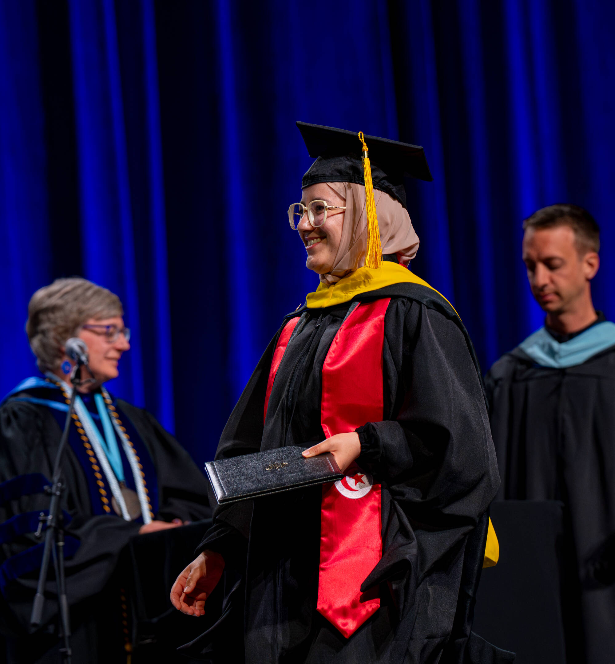 student walking across GVSU stage with diploma in hand